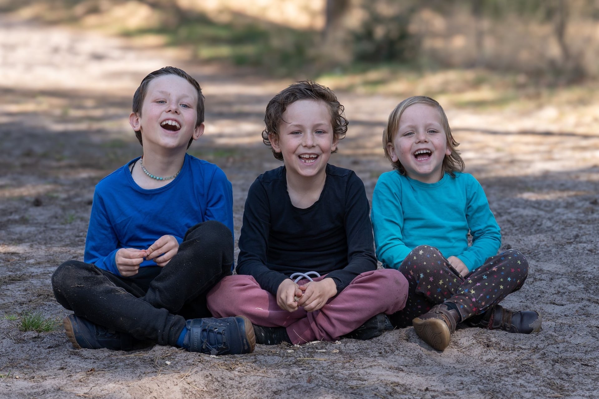 drie kinderen samen met elkaar als onderdeel van een gezinsfotosessie, ditmaal zonder ouders.