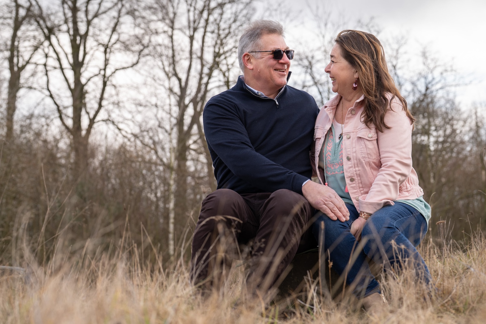 man en vrouw zittend op een boomstronk in het vroege voorjaar. De liefde spat van het verliefde stel af.