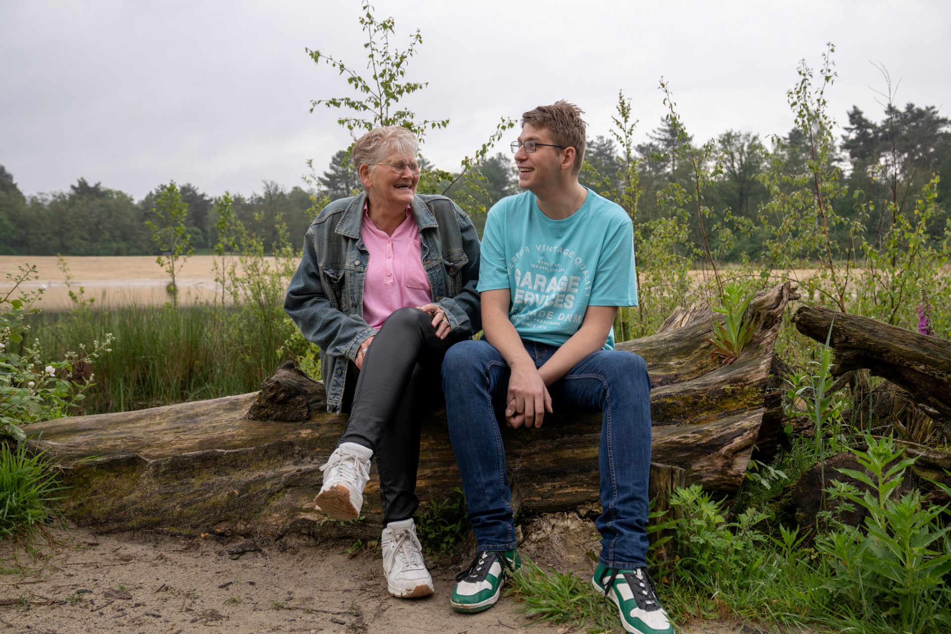 Moeder en zoon zitten op een boomstronk bij de bergse heide in bergen op zoom.
